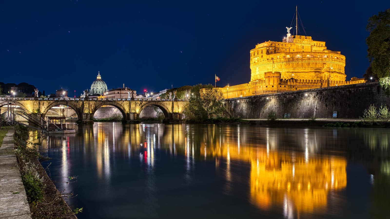 Castel Sant'Angelo photographed at blue hour from the Tiber, with the bronze Archangel Michael illuminated above the cylindrical fortress that once housed the Cagliostra cell