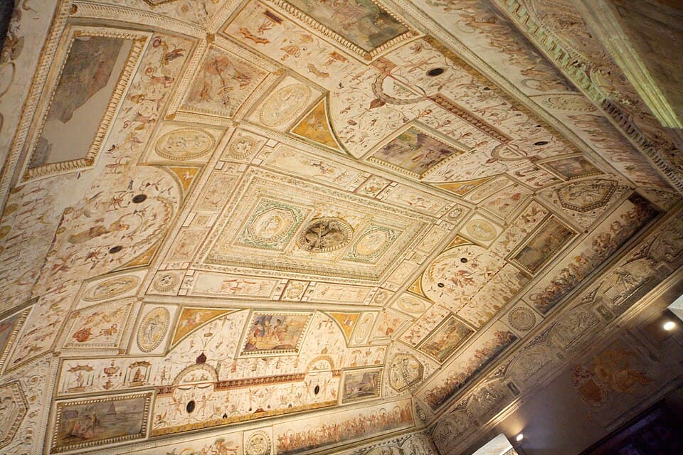 The east wall of the Sala della Biblioteca at Castel Sant'Angelo, with the Renaissance fireplace and, above it, the painted allegorical figures of the Church and Rome flanking the central Farnese papal coat of arms