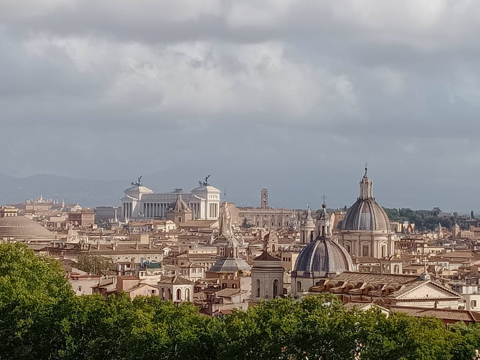 Panoramic view from the Terrazza dell'Angelo toward the historic centre of Rome, showing the white mass of the Altare della Patria, the dome of the Pantheon, and the rooftops of the Parione district