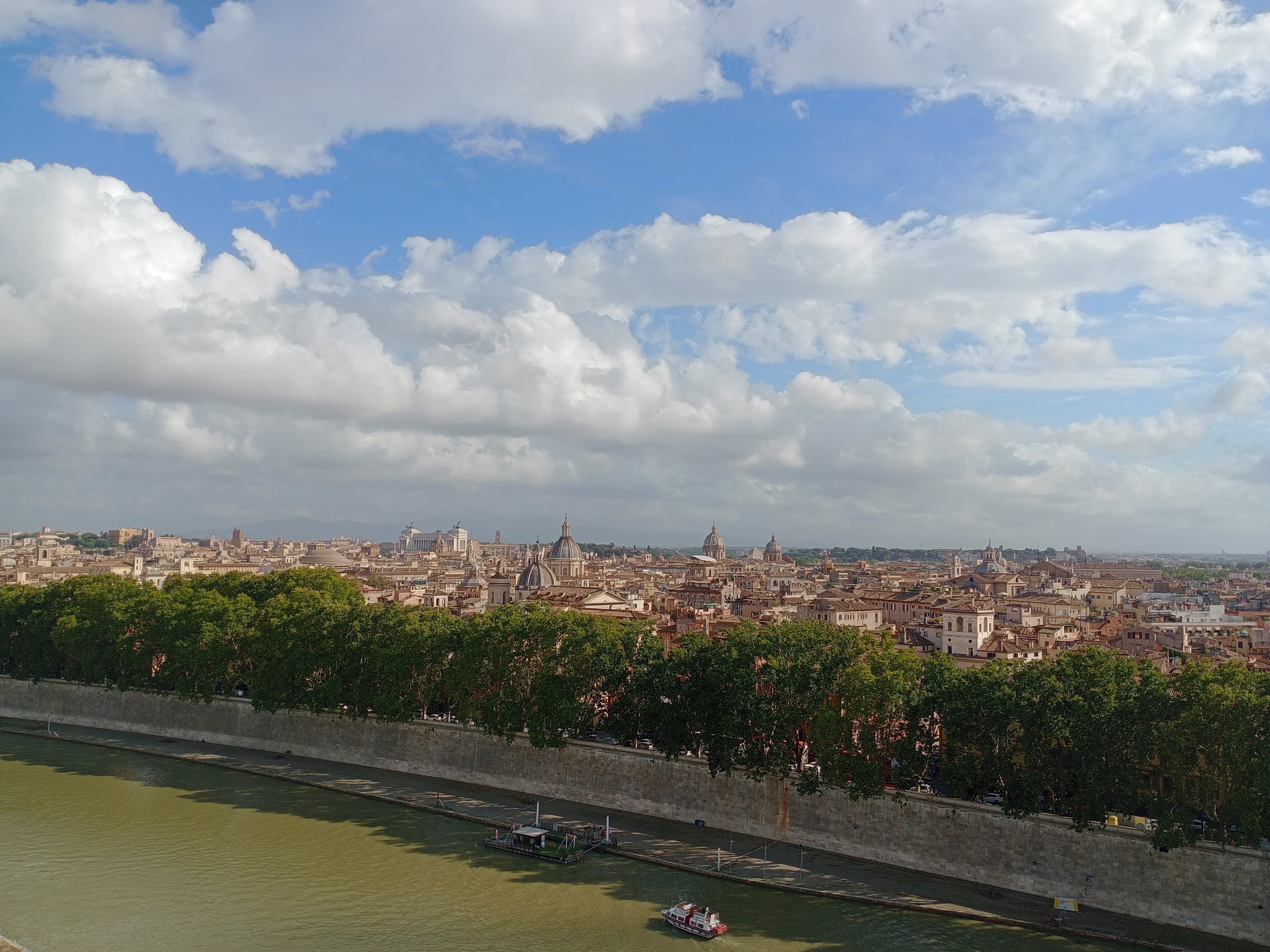 Panoramic view of Rome's historic center from Castel Sant'Angelo's terrace, with the Tiber river, Altare della Patria and the city's Baroque domes visible under a dramatic sky
